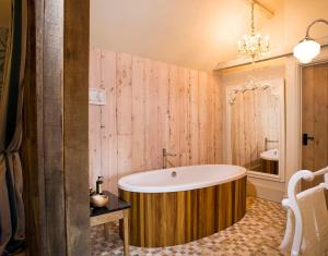 贝里圣埃德蒙兹The Fox by Greene King Inns的带浴缸的浴室和木墙