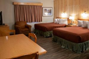 沃特顿公园阿斯彭村庄酒店的酒店客房设有两张床和一张桌子。