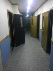 首尔The Core Albergue的一条空的走廊,走廊上设有门,走廊上设有一条长长的走廊