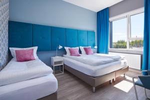 雷克雅未克ODDSSON Hotel的配有两张蓝色墙壁和粉红色枕头的客房内的床铺