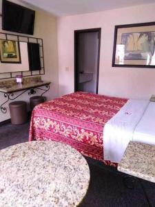 提华纳Hotel Descanso Inn的酒店客房设有两张床和一张桌子。