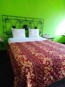 提华纳Hotel Descanso Inn的一间卧室配有一张带绿色墙壁的床
