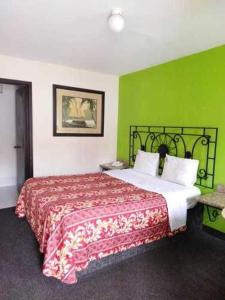 提华纳Hotel Descanso Inn的一间卧室配有一张带绿色墙壁的床