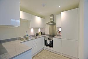 勒威克Modern Commercial Street Maisonette的厨房配有白色橱柜、水槽和炉灶。