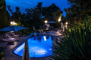 伊斯基亚Ischia Dream Sunset的夜间游泳池配有椅子和遮阳伞