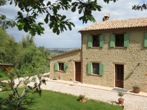 Fratte RosaB&B Casa Cuccagna的享有带绿色百叶窗的石屋的外部景色