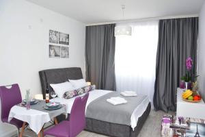 蒂瓦特Small Oasis Apartment的一间卧室配有一张床和一张带紫色椅子的桌子