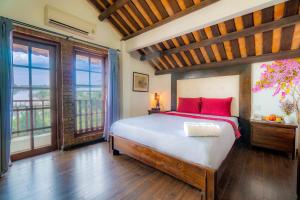 会安Calm House Hotel Hoi An 1的一间卧室配有一张带红色枕头的床和窗户。
