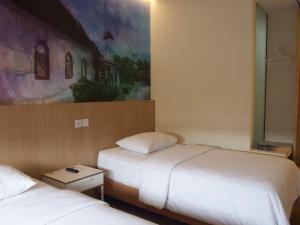 安汶城市酒店的酒店客房设有两张床,墙上挂有绘画作品