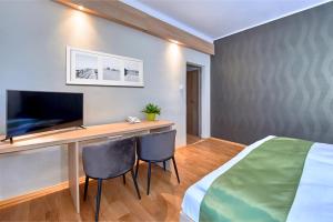 科瓦科瓦Hotel Kochau的一间卧室配有一张桌子、一台电视和一张床