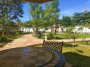 麦克坦皇家一号度假村 Tourist Garden Hotel的公园内带桌子和长凳的庭院