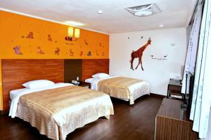 垦丁大街统茂高山青饭店的两张床铺,位于酒店房间,墙上挂着长颈鹿