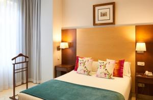 马德里萨拉曼卡区套房酒店的一间卧室配有一张带木制床头板和枕头的床。