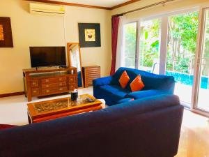 卡伦海滩Karon Pool Villa 卡伦3卧泳池别墅的客厅配有蓝色的沙发和电视
