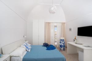阿纳卡普里Caprita Guest House的白色卧室配有蓝色的床和书桌