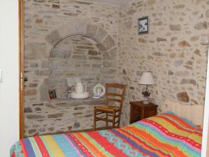 康卡勒L'Tas De Cailloux的一间卧室设有石墙、一张床和一把椅子