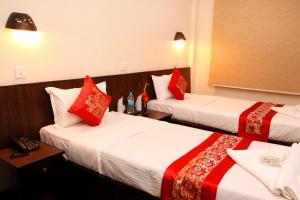 加德满都梦幻尼泊尔公寓酒店 的两张位于酒店客房的床铺,配有红色枕头