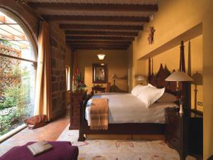 库斯科Monasterio, A Belmond Hotel, Cusco的一间卧室设有一张大床和一个大窗户