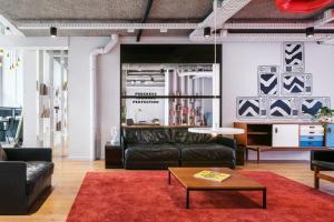 海牙The Social Hub The Hague的客厅配有黑色皮革家具和红色地毯。
