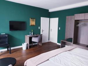 不莱梅Monopol Boutique Hotel的一间卧室设有绿色的墙壁、一张床和一张书桌
