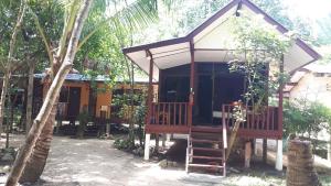 湄南海滩月亮小屋酒店的一个小房子,有门廊和一棵树