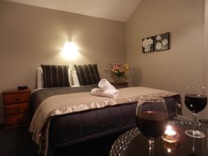 瓦纳卡瓦纳卡湖旅馆的一间卧室配有一张带两杯葡萄酒的床