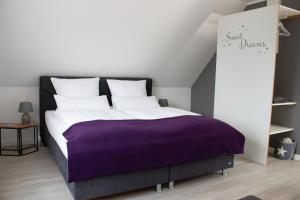 翁德洛Heideträume Appartements的一间卧室配有一张大床和紫色毯子