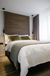 希奥利艾City Center Apartment in Siauliai的卧室配有一张白色大床和木制床头板