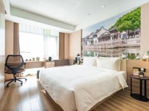 苏州苏州工业园区阳澄湖大道亚朵酒店的卧室配有一张大床,墙上挂有绘画作品