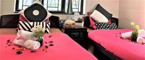 香港Cebu Inn的一间设有两张粉红色床单和鲜花的床的房间