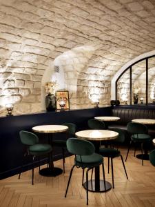 巴黎巴蒂尼奧勒浪漫约会酒店的一间带桌椅和石墙的餐厅