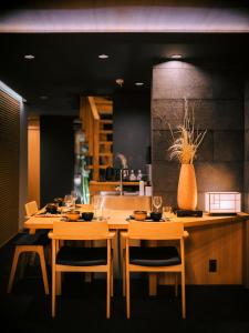 名古屋SAMURAI HOUSE Ⅱ的一间设有两张桌子的用餐室和墙上的花瓶