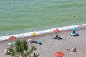 费特希耶柏林酒店 的海滩上有人,沙滩上摆放着椅子和遮阳伞