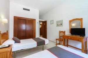 莫特里尔Hotel Costa Andaluza的一间卧室配有两张床、一张桌子和一台电视。