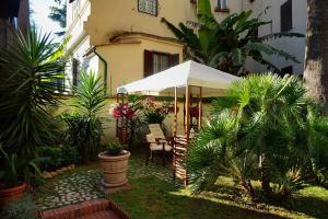 罗马格林酒店的一座花园,在一座建筑前配有白色遮阳伞