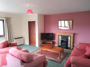 波马利斯Tyddyn Crwn Country-House Apartments的客厅配有2把粉红色的椅子和桌子