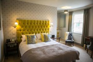 梅德斯通Leeds Castle Stable Courtyard Bed and Breakfast的一间卧室配有一张带黄色床头板的大床
