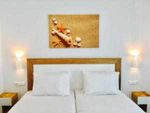 奥诺斯Eleftheria Hotel & Apartments的卧室配有一张带两个枕头的床,墙上挂有绘画作品