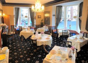 惠特比The Captain's Lodge accommodation的餐厅配有白色的桌椅和吊灯