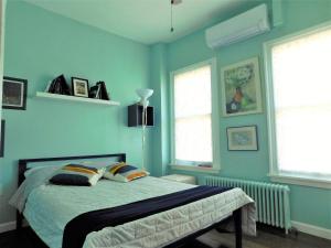 波士顿Private Rooms, Shared Bath in a Private Home Minutes From Logan Airport的一间卧室拥有蓝色的墙壁,配有一张带枕头的床。