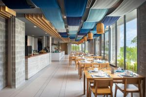 邦萨雷Cross Pattaya Oceanphere - formerly X2 Pattaya Oceanphere的餐厅设有木桌、椅子和窗户。