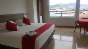 皮塔利托Hotel Grand Premium Plaza的一间卧室配有一张带红色枕头的大床和窗户