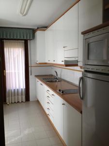 莱昂莱昂图里斯迪克普埃尔塔公寓酒店的厨房配有白色橱柜和不锈钢冰箱