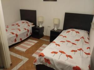 比尔杰卢特拉旅馆的一间卧室设有两张铺有红色叶子的床铺。