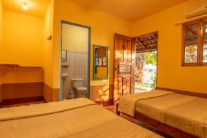 波波约Club Surf Popoyo的黄色客房 - 带两张床和一间浴室