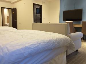 马公美心民宿的卧室配有白色的床和平面电视。