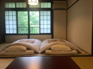 箱根箱根温泉 汤宿 山之省的一张大床,位于带两个窗户的房间
