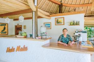 乌鲁瓦图姆玛热带住宿加早餐旅馆的坐在餐厅柜台上的男人