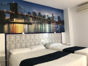 阿尔姆尼卡Hotel Playa San Cristóbal的一间带两张床的卧室和一张城市的大壁画