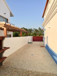 孔波尔塔Casa Oliveiras的一座带白色墙壁和栅栏的房屋的庭院